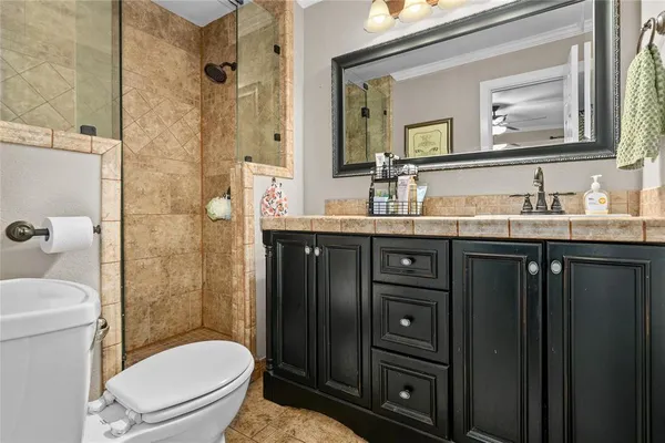 a bathroom with a granite countertop toilet sink shower and mirror
