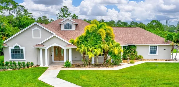 a front view of a house with a yard and green space