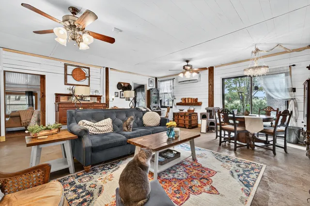 a living room with furniture kitchen view and a chandelier