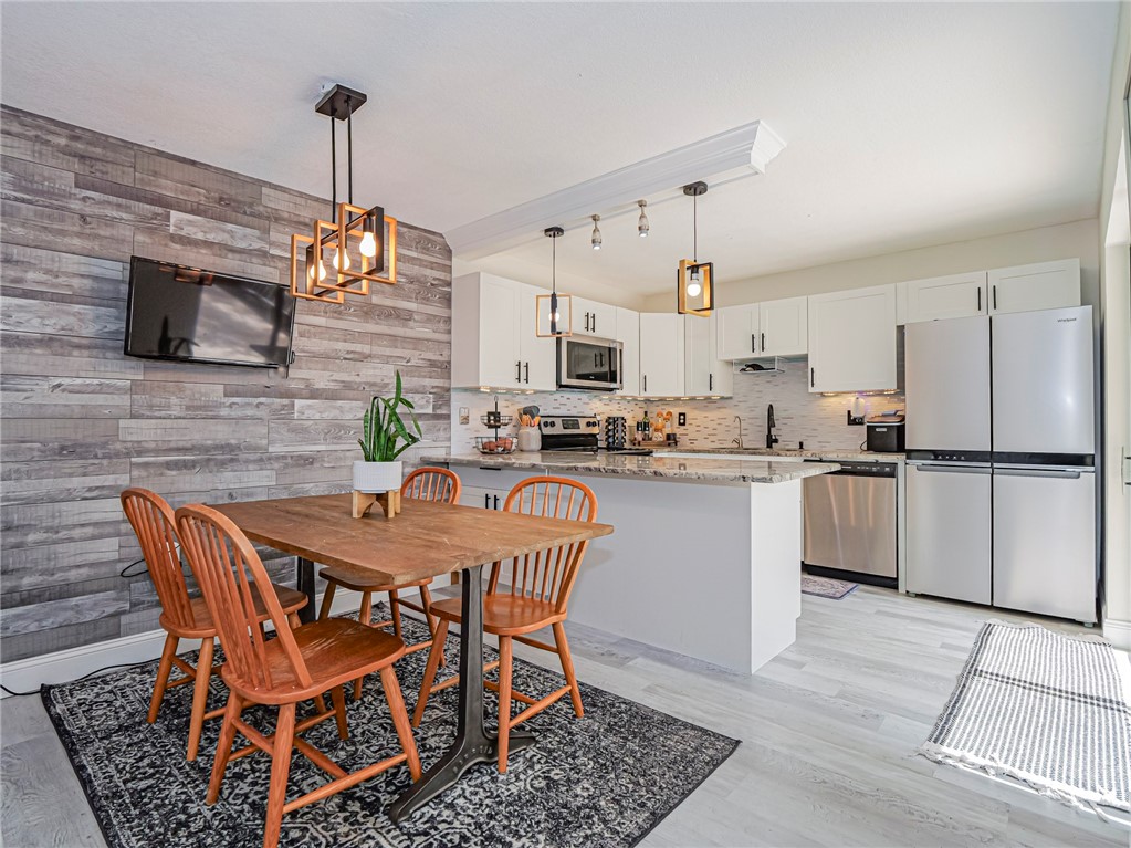 a kitchen with stainless steel appliances kitchen island granite countertop a dining table chairs and a refrigerator