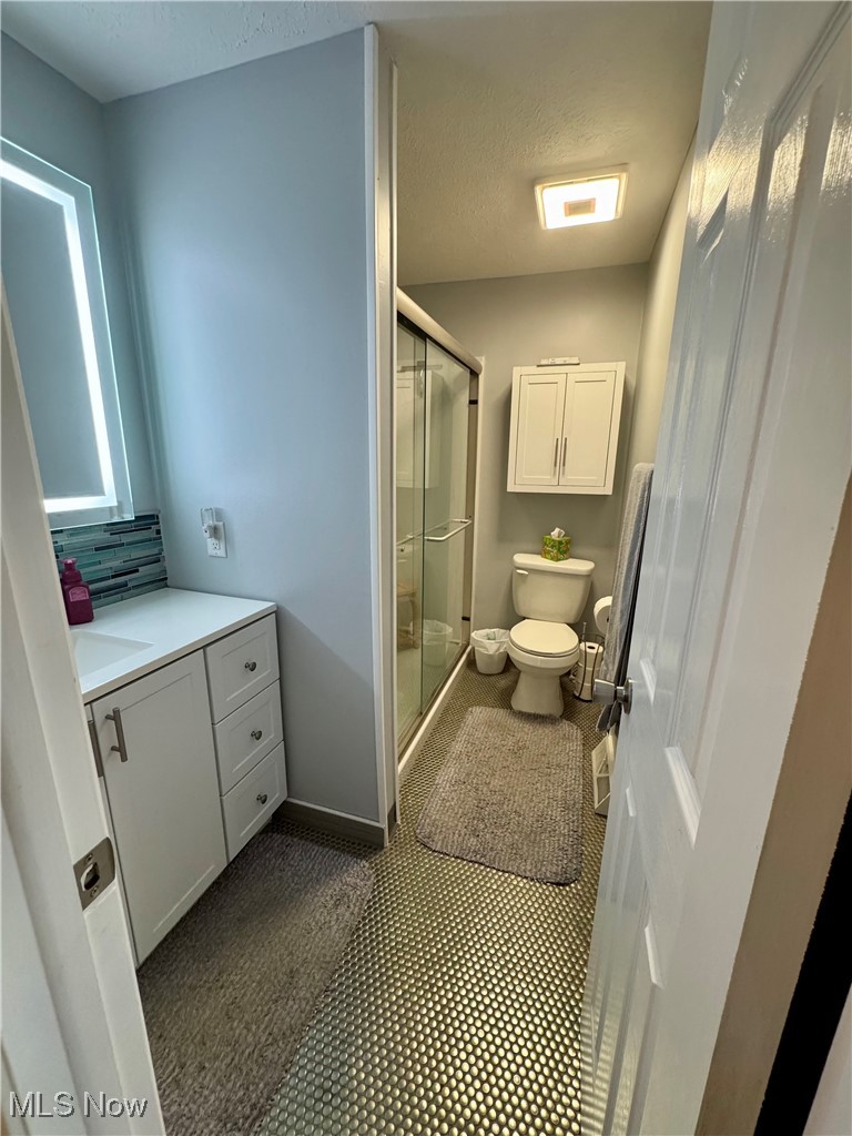 8949 West Ridge Road, Unit B Elyria, OH 44035 - Photo 18 of 24 Bathroom with vanity, a shower stall, a textured ceiling, and tile patterned flooring