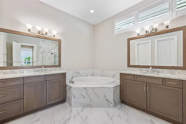 a bathroom with a double vanity sink mirror and bathtub