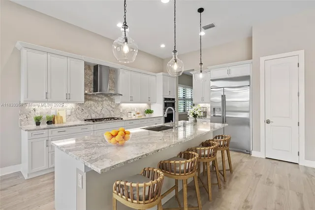 a kitchen with stainless steel appliances granite countertop a kitchen island hardwood floor and a sink