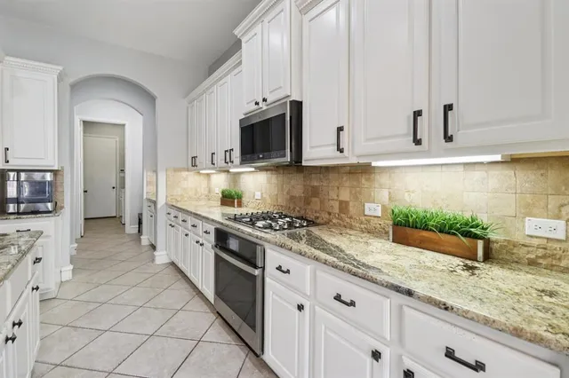 a kitchen with stainless steel appliances granite countertop a stove a sink and a microwave