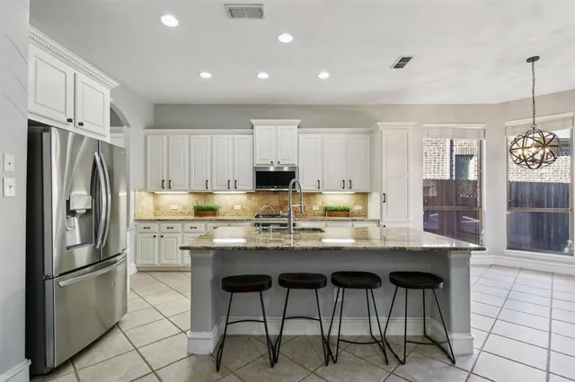 a kitchen with stainless steel appliances a dining table a stove a refrigerator and cabinets