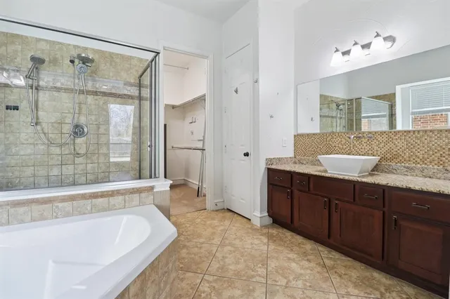a spacious bathroom with a tub sink shower and mirror