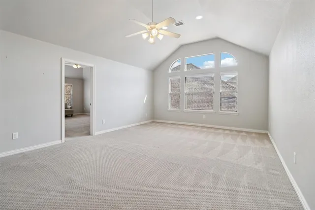 an empty room with a chandelier fan and windows