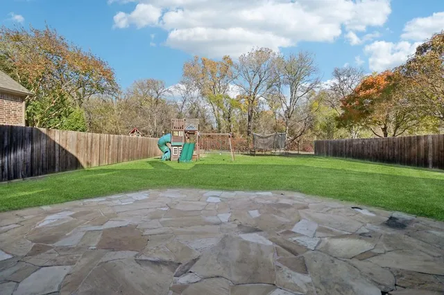 a view of a park with large trees and wooden fence