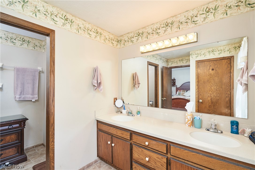 3097 Baughman Road Clinton, OH 44216 - Photo 17 of 27 Double vanity with undermount sinks, laminate countertop, heated flooring, and wood-finish cabinetry