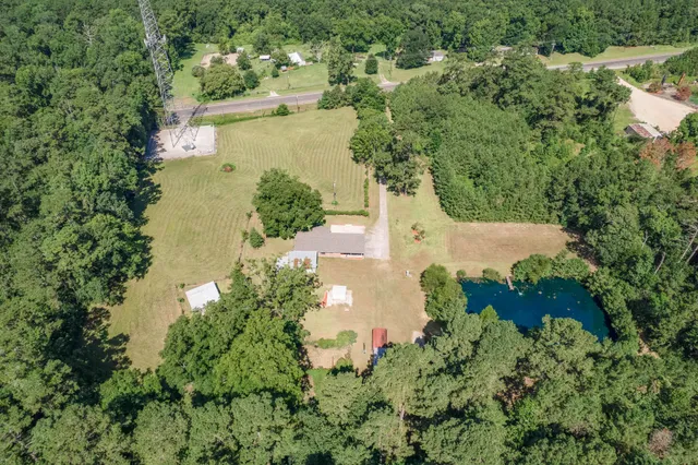 an aerial view of a residential houses with outdoor space and trees all around