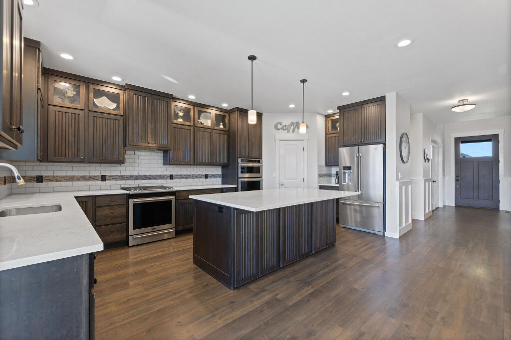 344 Northwest Saddle Ridge Loop Prineville, OR 97754 - Photo 33 of 64 a kitchen with stainless steel appliances kitchen island granite countertop a table chairs a sink and a refrigerator