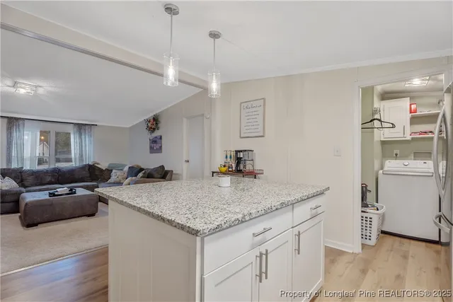 a view of a kitchen island a sink wooden floor and a living room