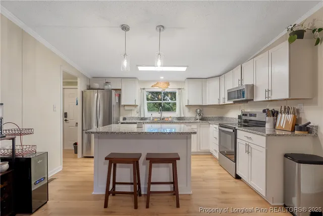 a kitchen with stainless steel appliances granite countertop a kitchen island hardwood floor sink stove dining table and chairs