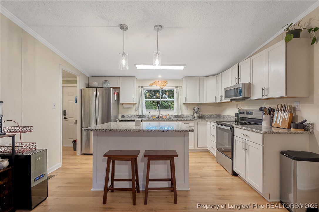 54 West Tryon Court Spring Lake, NC 28390 - Photo 10 of 43 a kitchen with stainless steel appliances granite countertop a kitchen island hardwood floor sink stove dining table and chairs