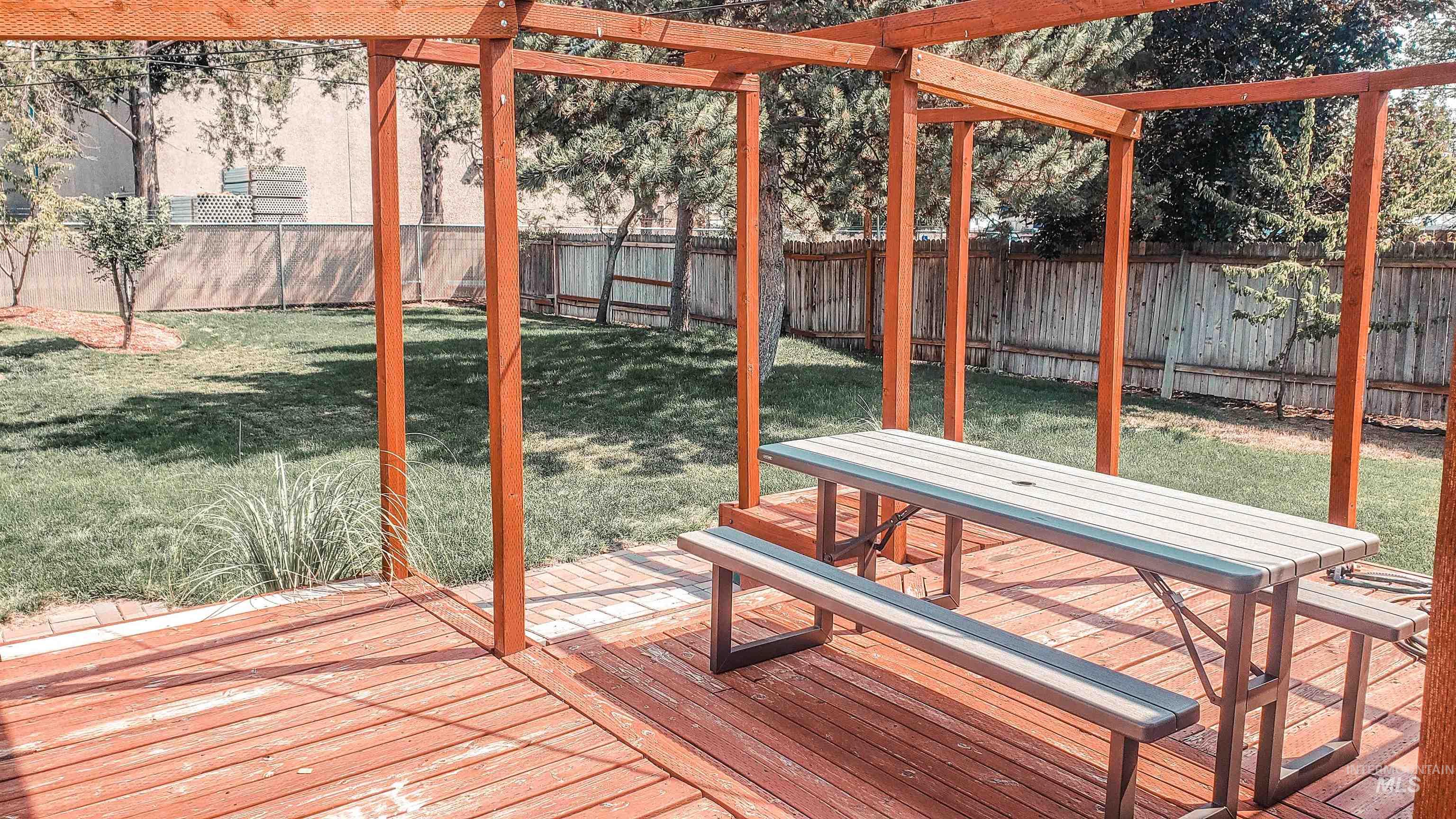 814 Baker Street Boise, ID 83706 - Photo 26 of 26 Spacious backyard featuring a wood deck, pergola structure, and a manicured lawn
