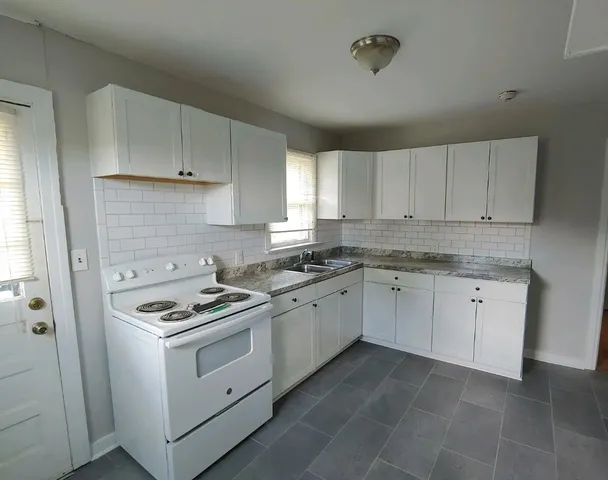 a kitchen with cabinets appliances a sink and a window