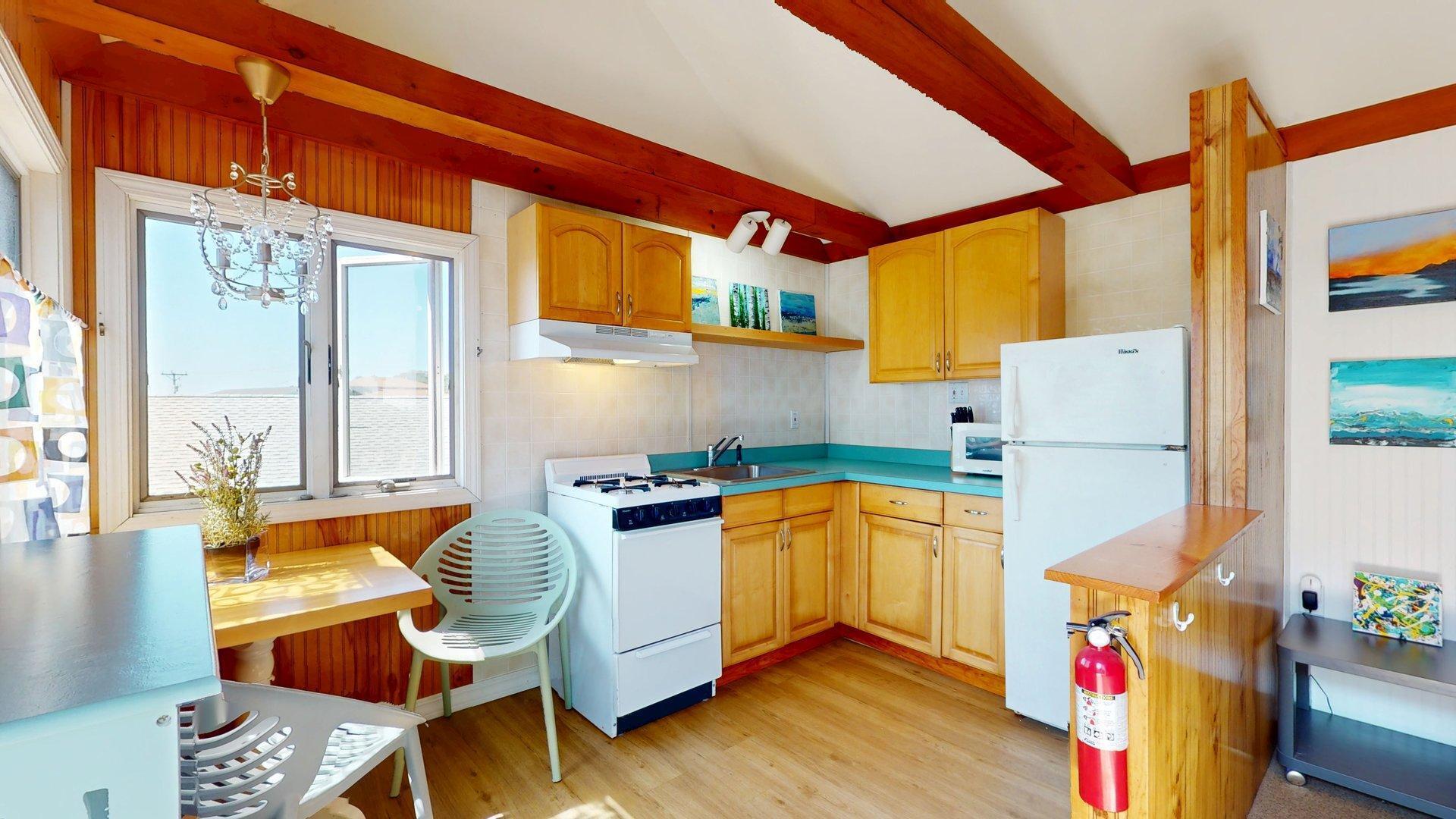 168 Shore Road, Unit 9 Truro, MA 02666 - Photo 10 of 33 a kitchen with stainless steel appliances granite countertop a sink a stove a refrigerator a dining table and chairs with wooden floor