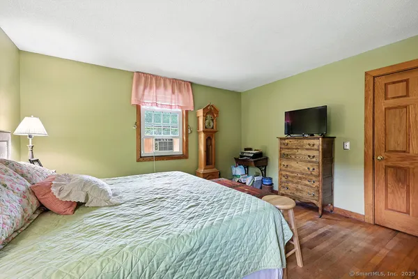 a bedroom with a bed and a flat tv screen on dresser