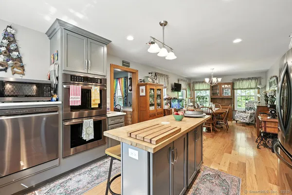 a kitchen with stainless steel appliances kitchen island granite countertop a table chairs and a refrigerator