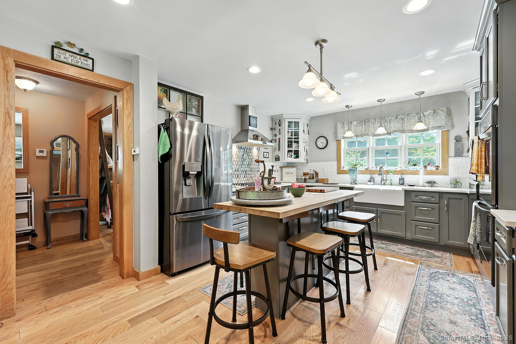 186 Mill Street Hartland, CT 06091 - Photo 6 of 33 a kitchen with stainless steel appliances granite countertop a refrigerator a stove a sink a dining table and chairs with wooden floor