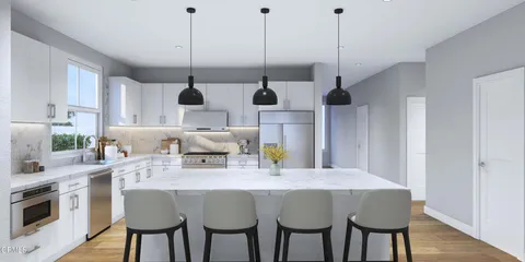 a kitchen with stainless steel appliances kitchen island granite countertop a table chairs and a wooden floor