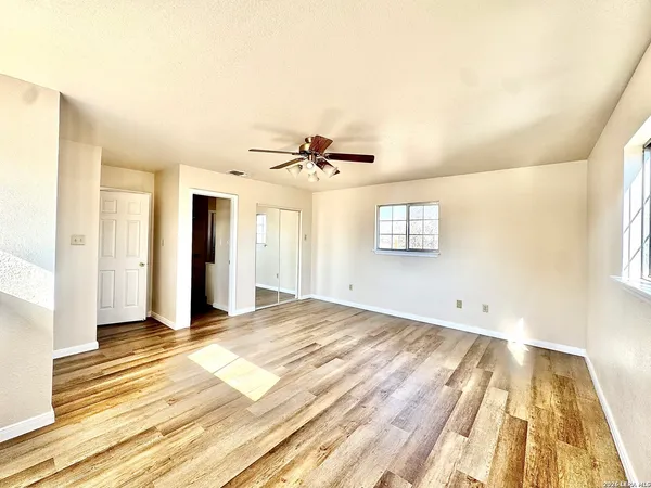a view of empty room with wooden floor and fan