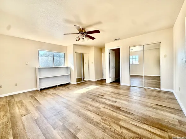 a view of empty room with wooden floor and fan