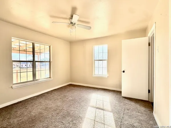 an empty room with wooden floor fan and windows
