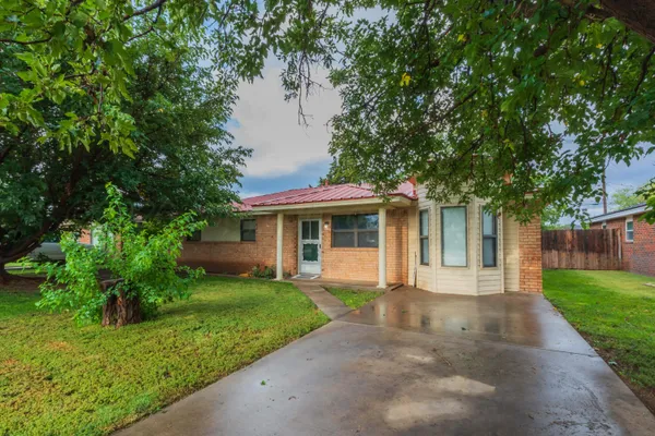 a front view of a house with a garden and trees