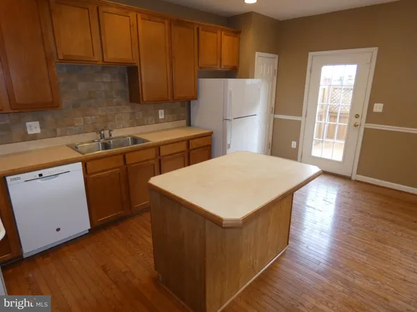 a kitchen with kitchen island a sink a stove a refrigerator and wooden cabinets
