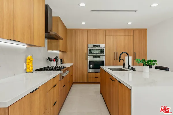 a kitchen with kitchen island granite countertop a sink stove and cabinets