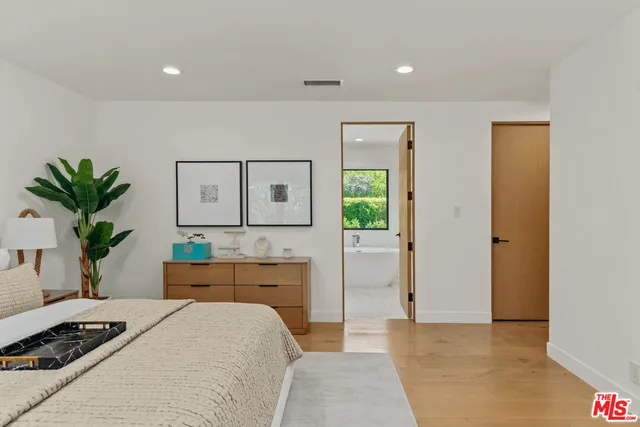 a bedroom with a bed and a potted plant on the dresser