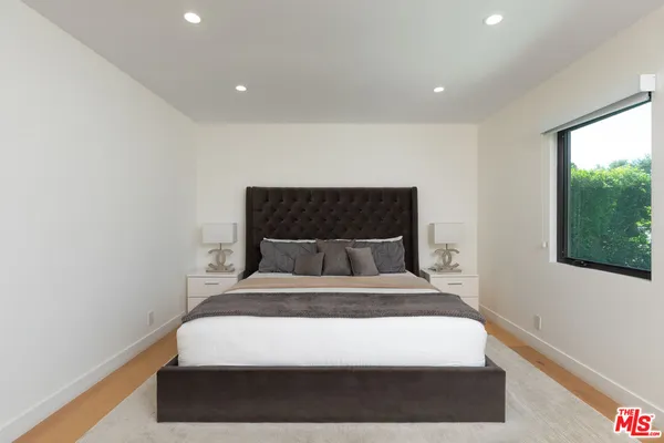 a bed sitting in a spacious bedroom next to a window