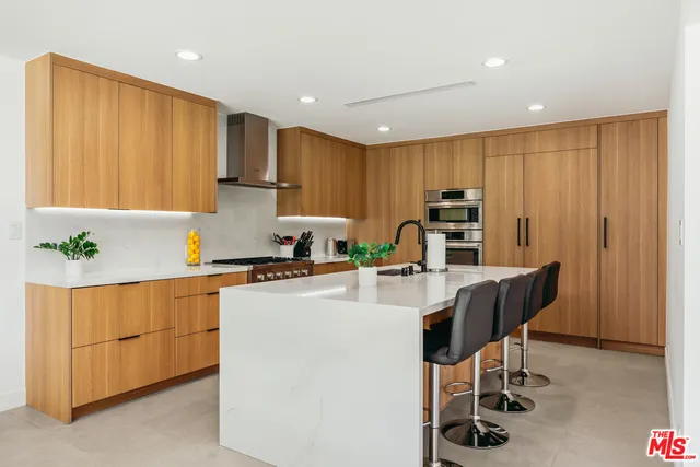 a kitchen with kitchen island a stove a table and chairs in it