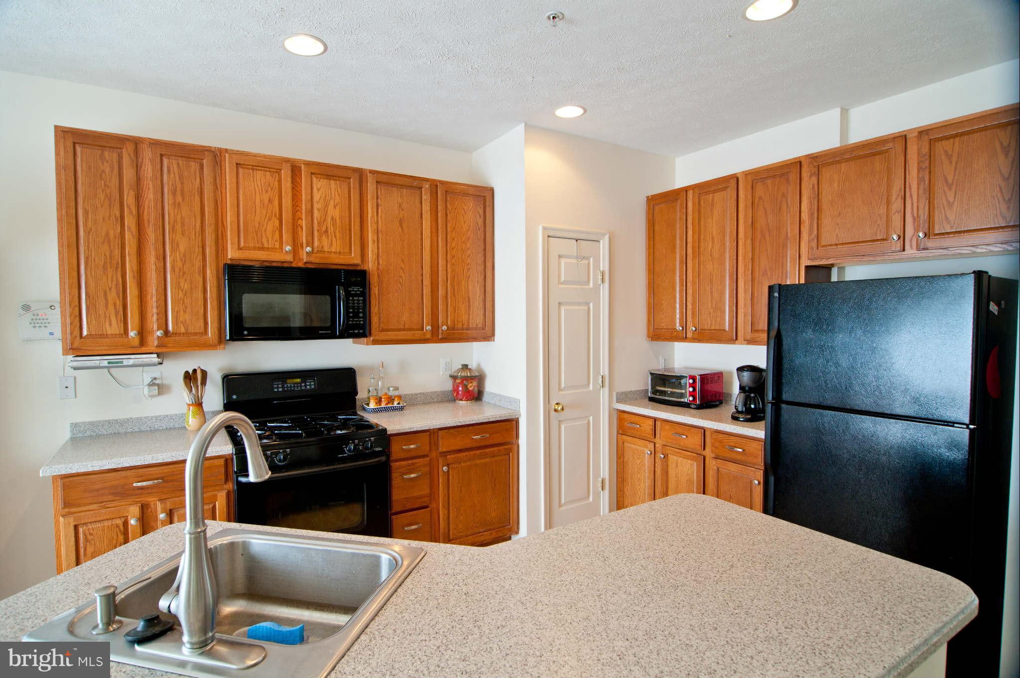 9661 Biggs Road Baltimore, MD 21220 - Photo 8 of 25 a kitchen with stainless steel appliances granite countertop a refrigerator stove top oven a sink dishwasher and wooden cabinets
