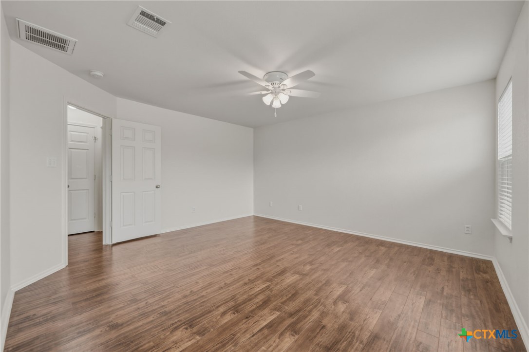 109 Comal Cove Elgin, TX 78621 - Photo 24 of 34 an empty room with wooden floor and fan