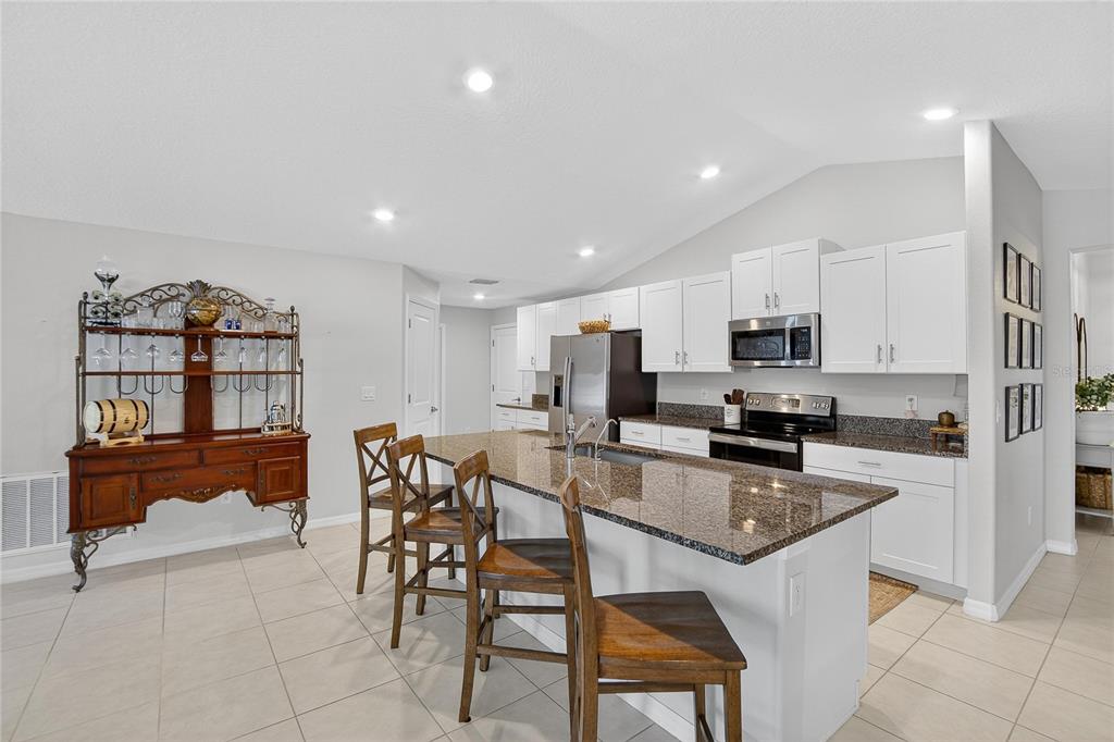 2950 Flying Blackbird Road Bartow, FL 33830 - Photo 13 of 41 a kitchen with stainless steel appliances granite countertop a stove top oven a sink a dining table and chairs with wooden floor