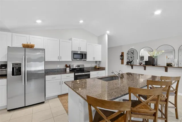 a kitchen with stainless steel appliances granite countertop a refrigerator a stove a sink a dining table and chairs