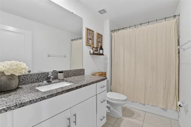 a bathroom with a granite countertop sink a toilet and a mirror