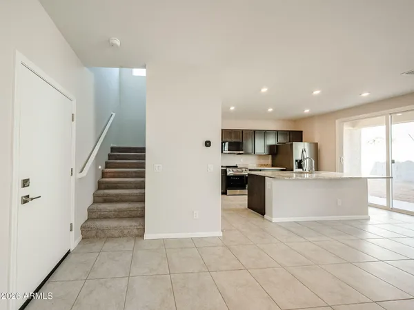 a large white kitchen with kitchen island a sink a counter top space and stainless steel appliances