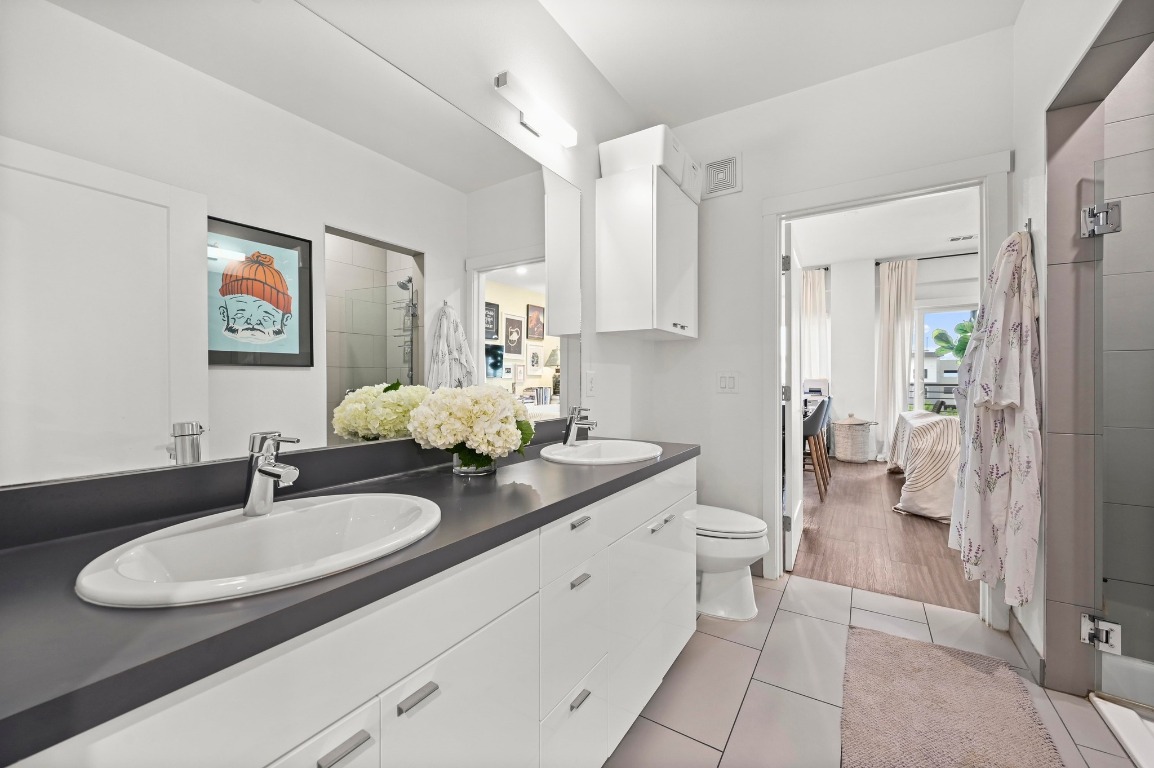 4361 South Congress Avenue, Unit 427 Austin, TX 78745 - Photo 15 of 33 a bathroom with a granite countertop sink a toilet and a mirror
