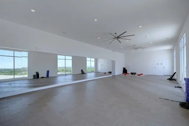 an empty room with windows and ceiling fan