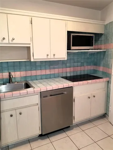 a kitchen with white cabinets and refrigerator