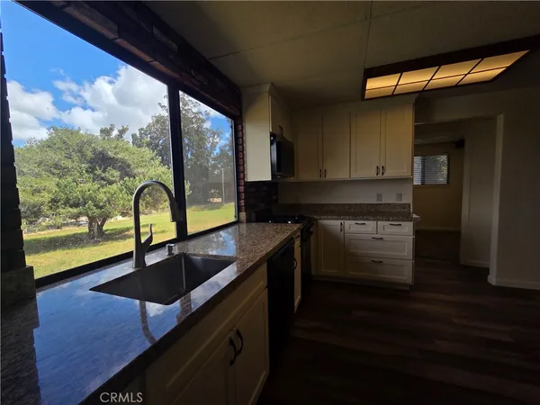 a kitchen with granite countertop a sink a counter top space and cabinets