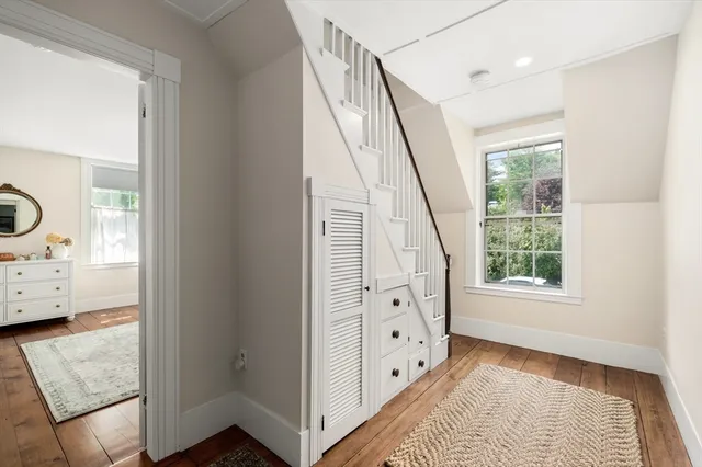 a view of hallway with window and wooden floor
