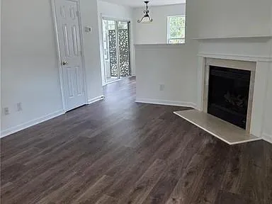 an empty room with wooden floor fireplace and windows
