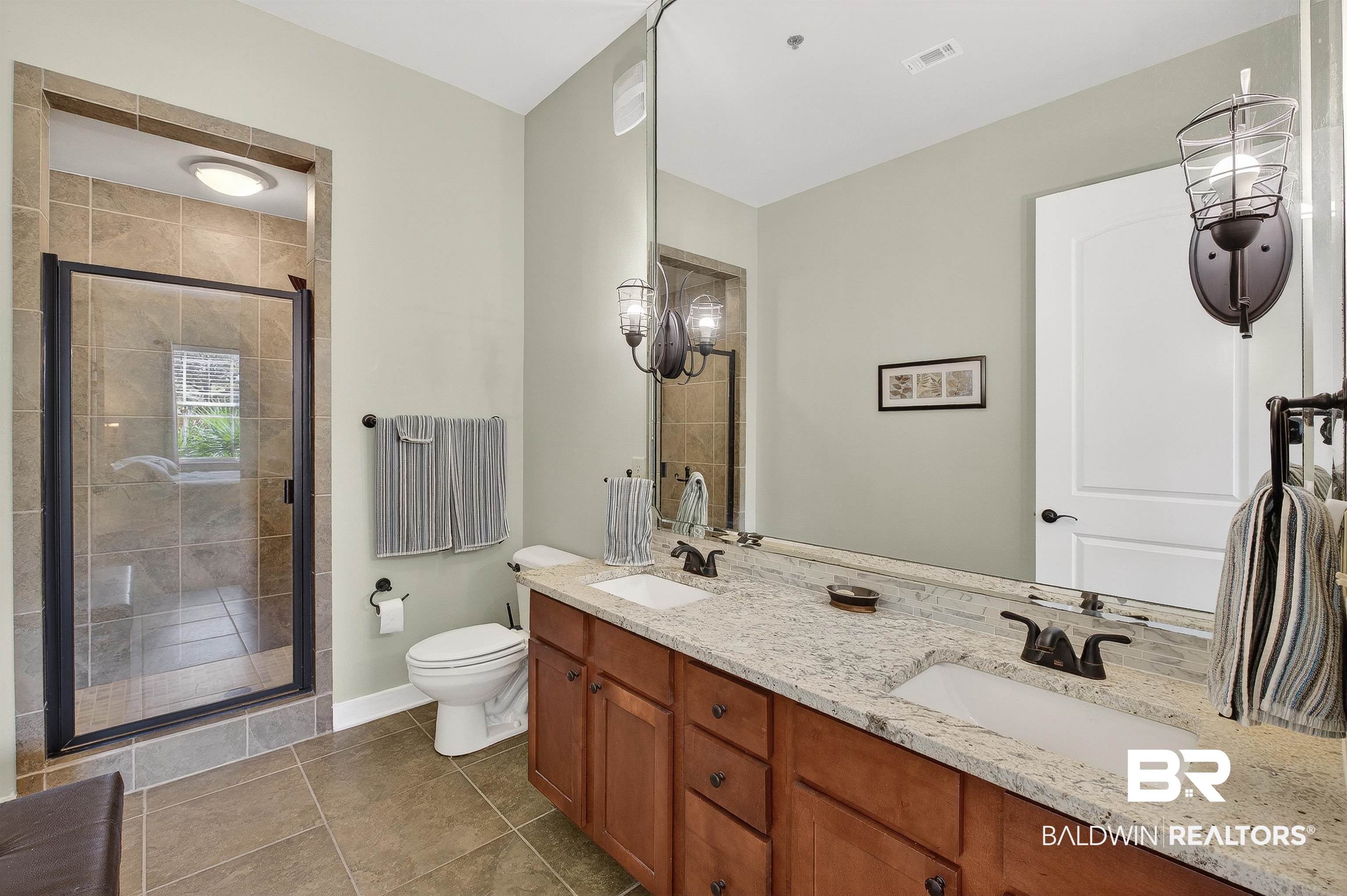 1430 West Regency Road, Unit I102 Gulf Shores, AL 36542 - Photo 16 of 31 Full bathroom with double vanity, a shower stall, and dark tile patterned flooring