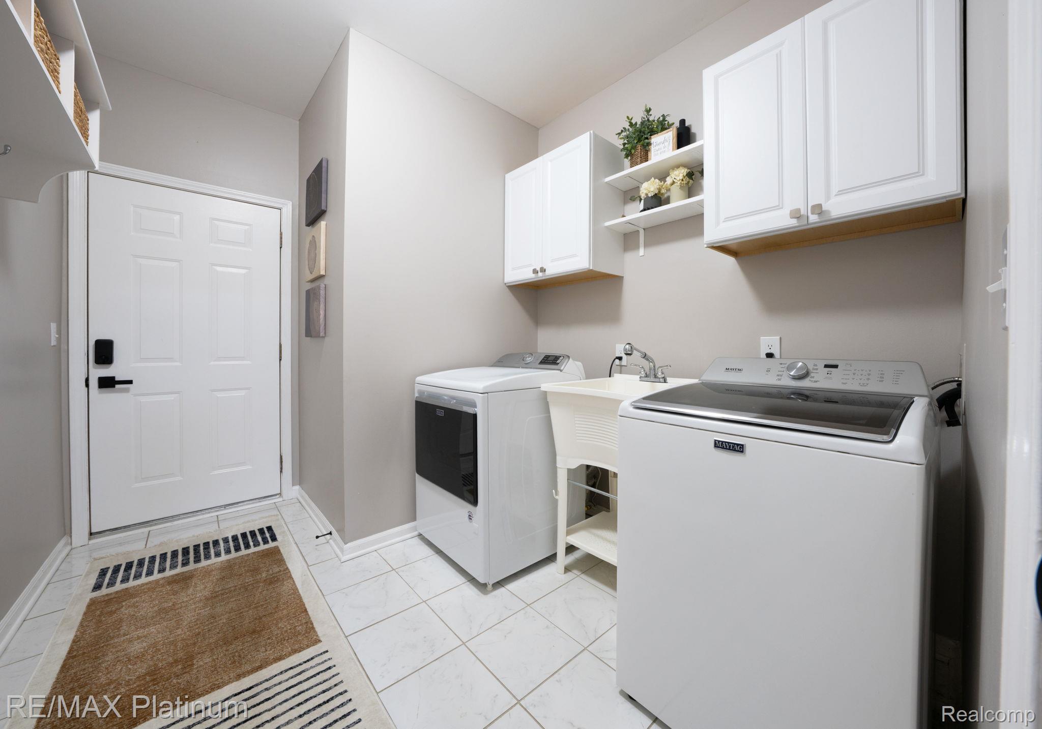 4253 Hampton Ridge Boulevard Howell, MI 48843 - Photo 19 of 32 Main floor laundry room featuring washer and clothes dryer, cabinet space, and utility sink