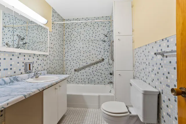 a bathroom with a granite countertop toilet a sink a mirror a bathtub and shower