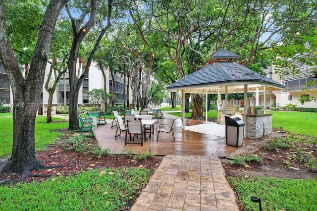 a view of a patio with table and chairs potted plants and a large tree